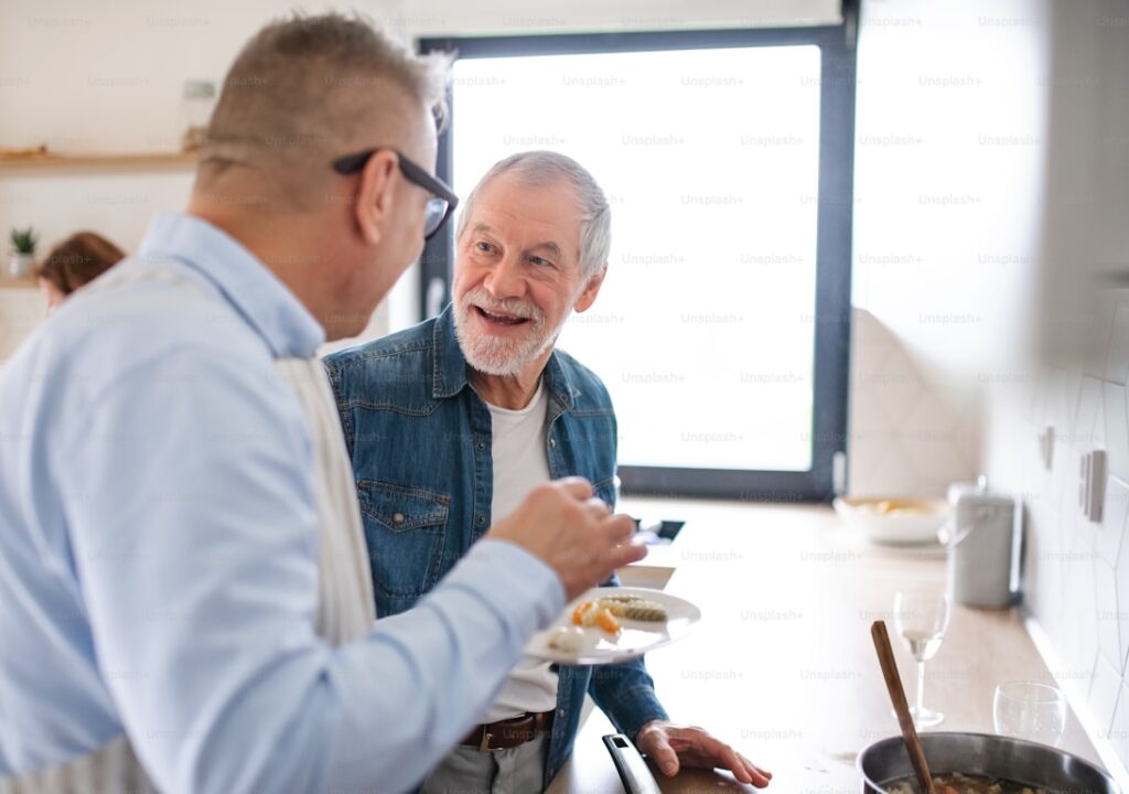 Ung mann som snakker med eldre mann ved kjøkkenbordet